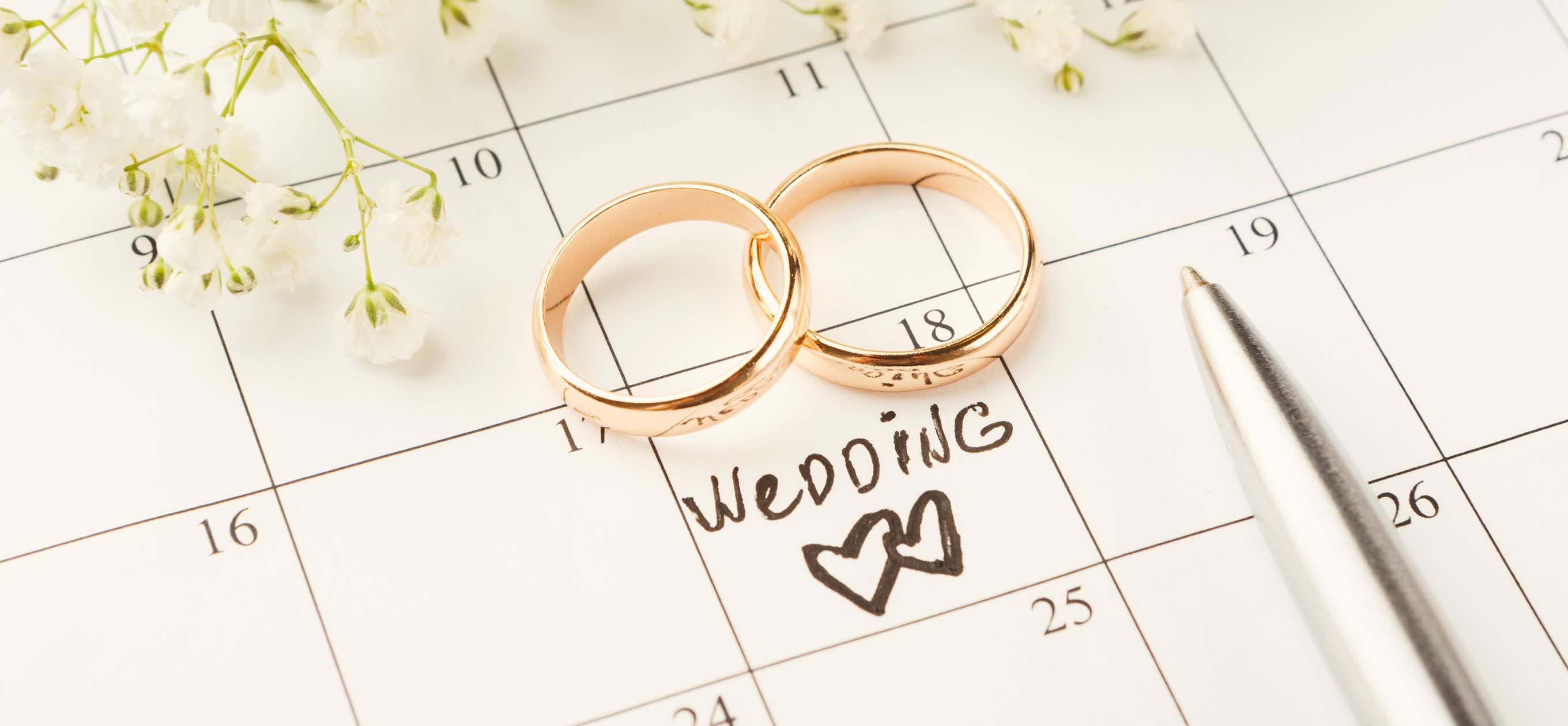 Dva snubní prsteny na kalendáři s datem označeným nápisem Wedding a srdíčkem