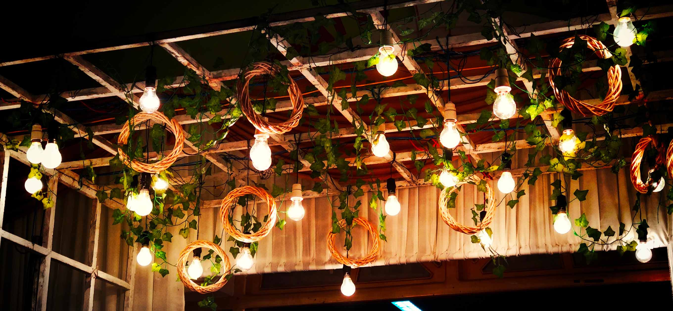 Večerní svatební výzdoba — pergola se žárovkami, proutěnými věnci a zelení